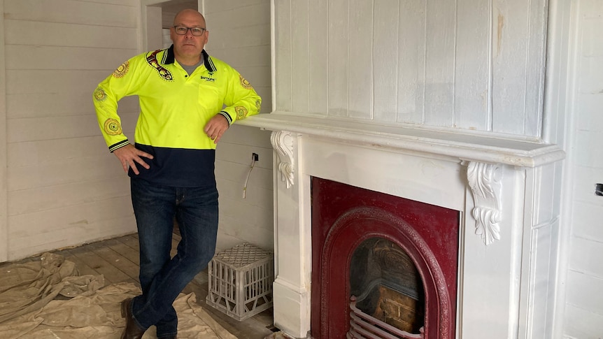 A man poses next to a fire place