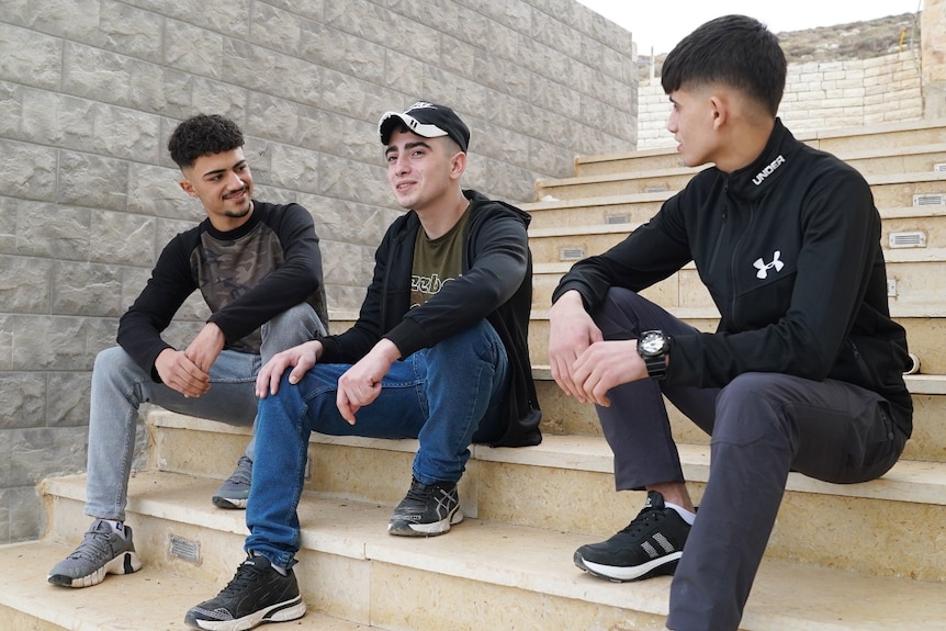Three boys sitting on some steps, talking