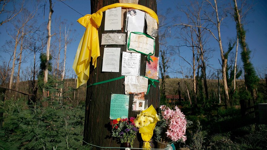Flowers and messages are placed on a fire-damaged tree on the anniversary of Black Saturday.