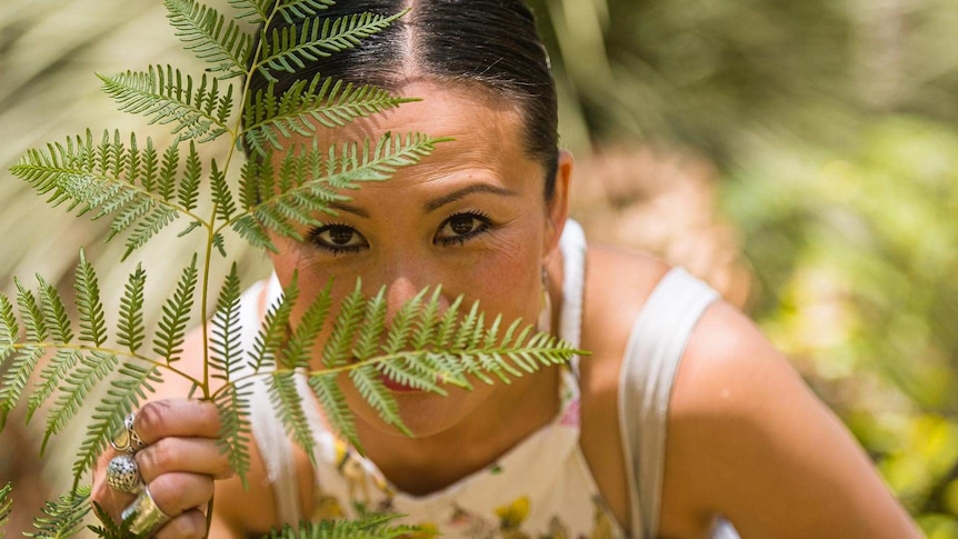 Poh Ling Yeow looking at camera through a piece of bracken