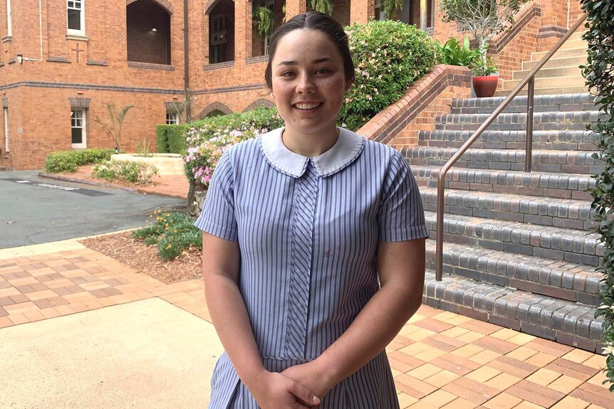 A school student in uniform standing outside a private school