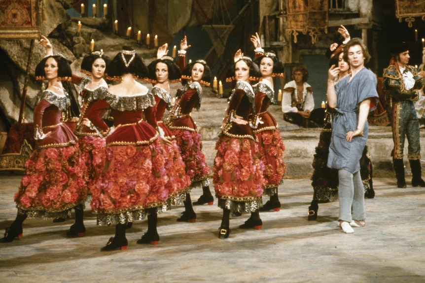 One male ballet dancer with eight female dancers in red costumes.