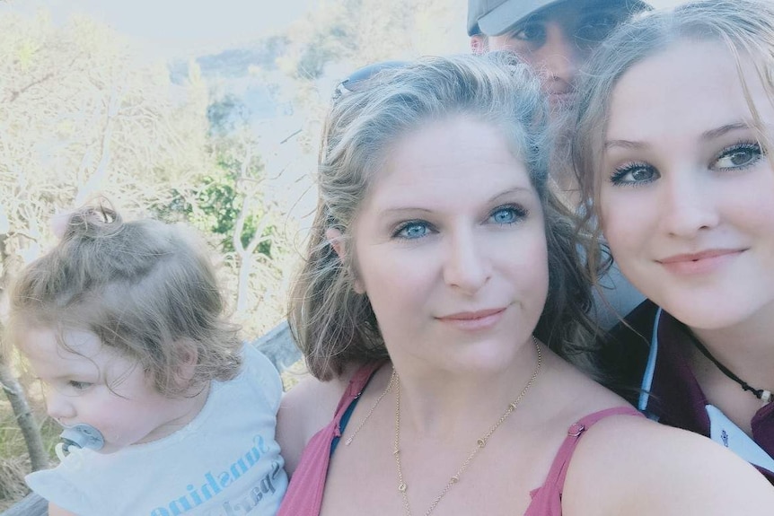 A young woman and her three children stare to the right of the camera