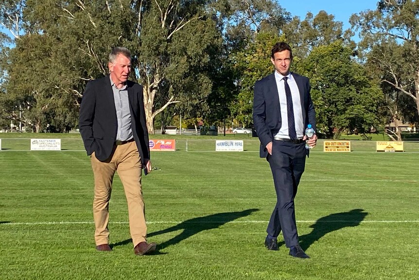 Two men walk across a football field in Albury, New South Wales