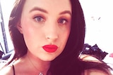 A selfie of Olivia Mead with dark hair and red lipstick.