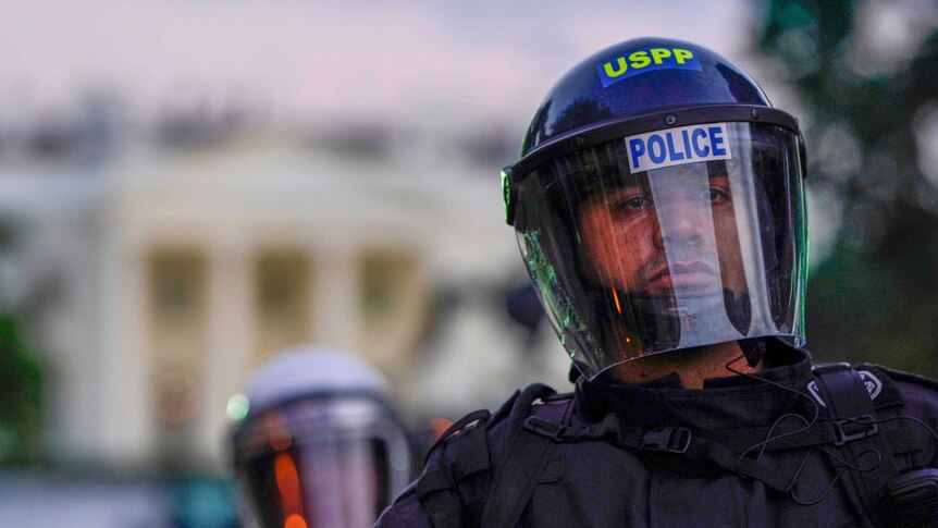 Police in riot gear stand in front of the White House