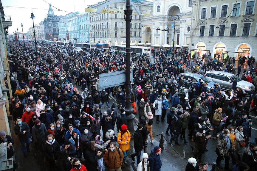 Un gran numero di persone sta camminando lungo una strada di protesta a San Pietroburgo, in Russia, con tempo molto freddo.