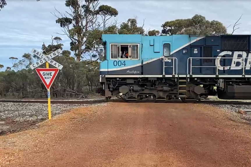 Blue trail drives through a rail crossing with a give way sign. 