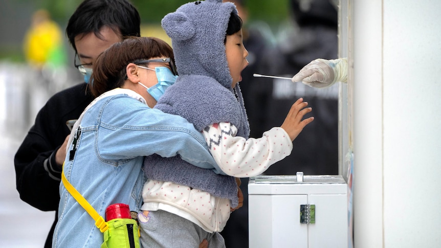 A child receives a throat swab for a COVID-19 test at a testing site in Beijing