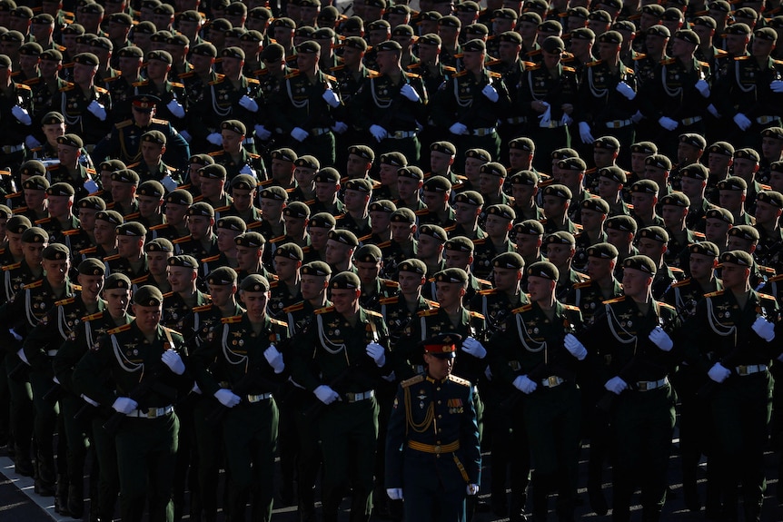 A large number of Russian soldiers standing in perfect columns with white gloves standing out. 
