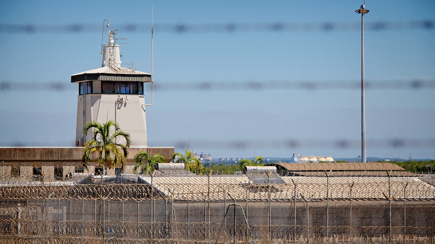 The exterior of the Don Dale Youth Detention Centre, with barbed wire in the foreground. 