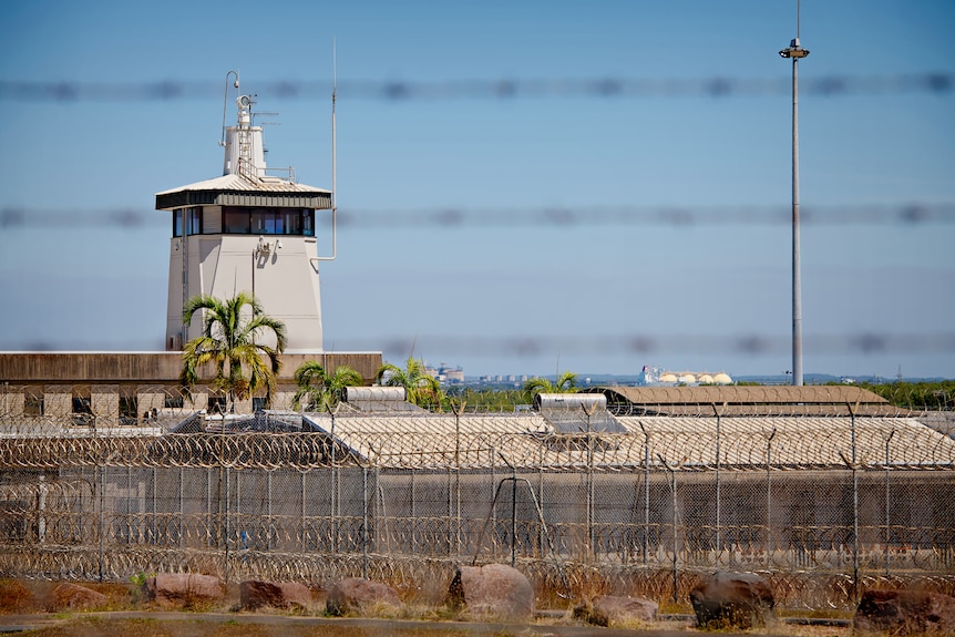 The exterior of the Don Dale Youth Detention Centre, with barbed wire in the foreground. 