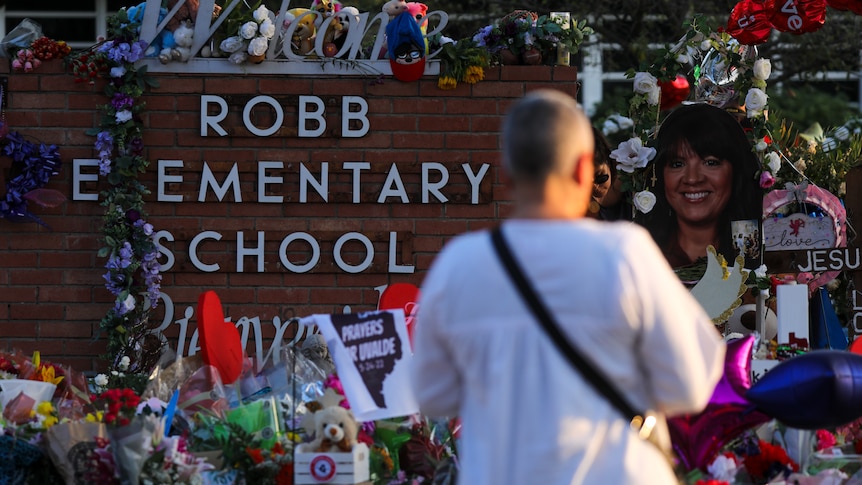 A woman stands in front of a memorial to the victims of Robb Elementary school shooting