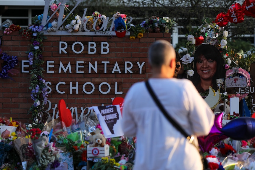 A woman stands in front of a memorial to the victims of Robb Elementary school shooting