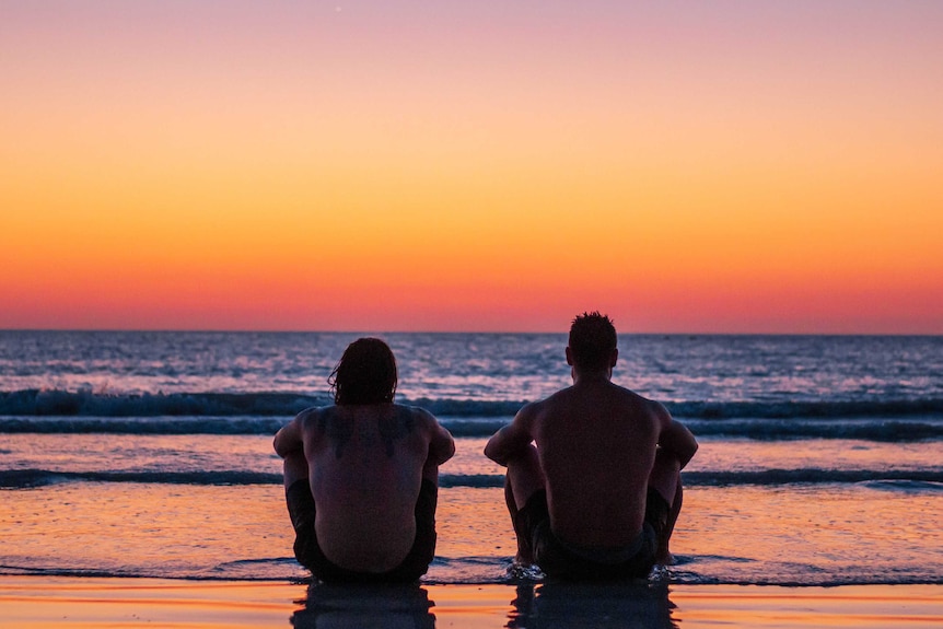 Two men watch the sunset on Broome's Cable Beach