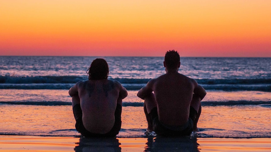 Two men watch the sunset on Broome's Cable Beach