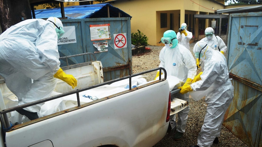 Red Cross workers in Guinea carry the body of an Ebola victim in near a hospital in Conakry on September 14, 2014.