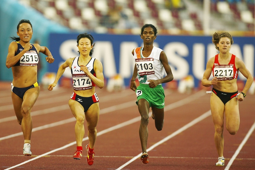 Four women run on a race track in their country's colours at the Asian Games.