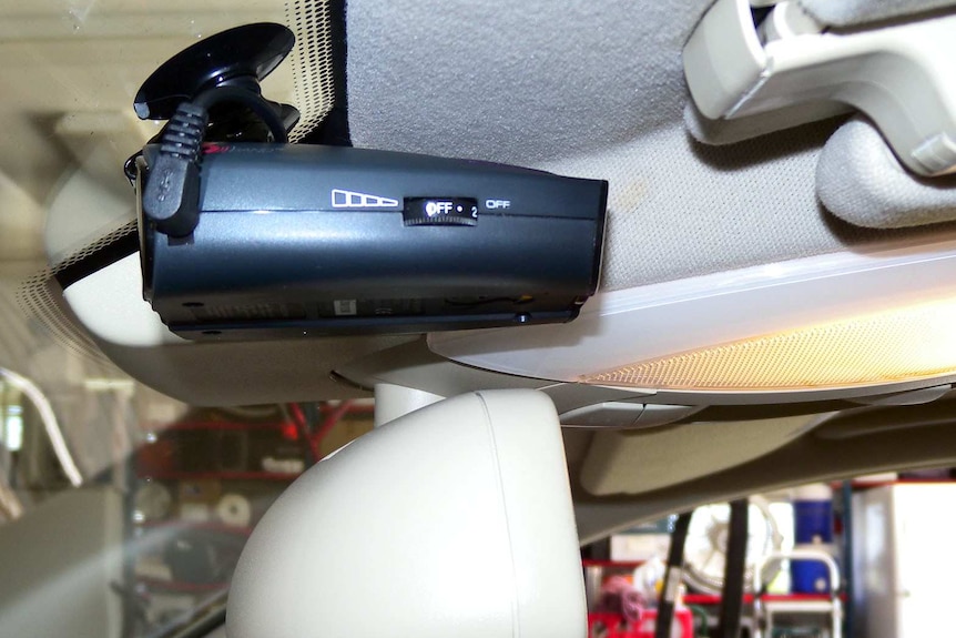 A car interior with a black device fixed to the winscreen.