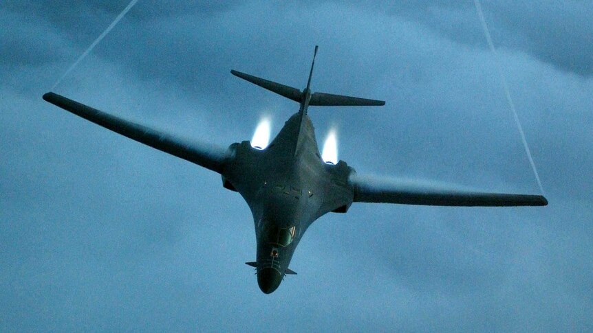 A US Air Force bomber flies through blue sky.