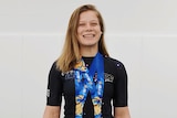 Nora Naomi Schultz smiles with two large, square gold medals around her neck.