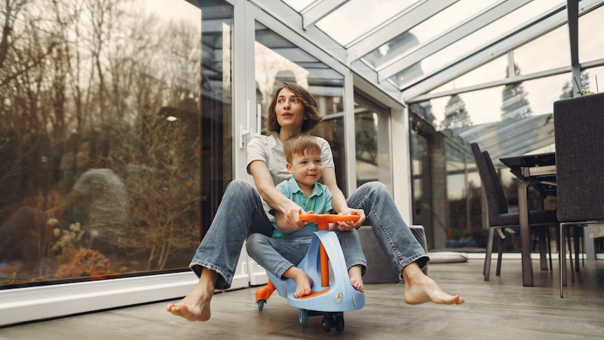 A woman rides behind her young son on a small bike