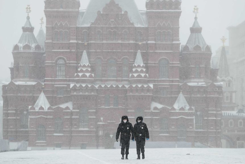 Two Russian soldiers in face masks walk through an empty Red Square in Moscow