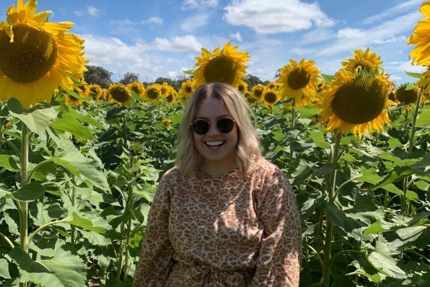Woman standing in front of sunflowers 
