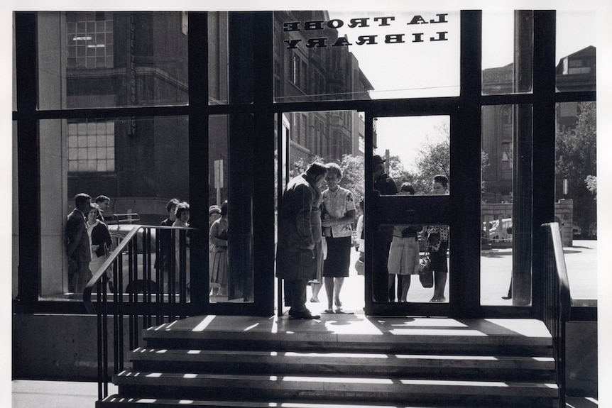 View through window of people lining up on the street to enter a building.