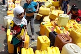 Yemeni children wait to get water