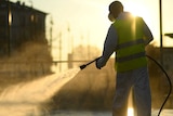 A worker in a vest sprays the streets of Milan with disinfectant as the sun rises.