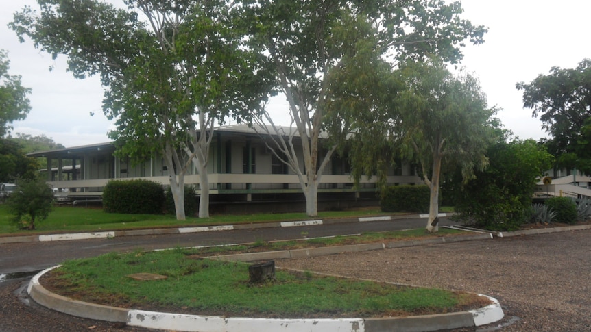 A government building along a road fronted by gum trees.