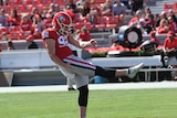An American football player punts the ball.