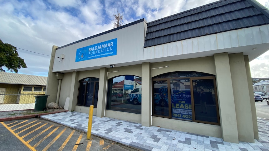 The entrance to the front of the Baldjamaar foundation office. a for lease sign is in the window anda baldjamaar banner