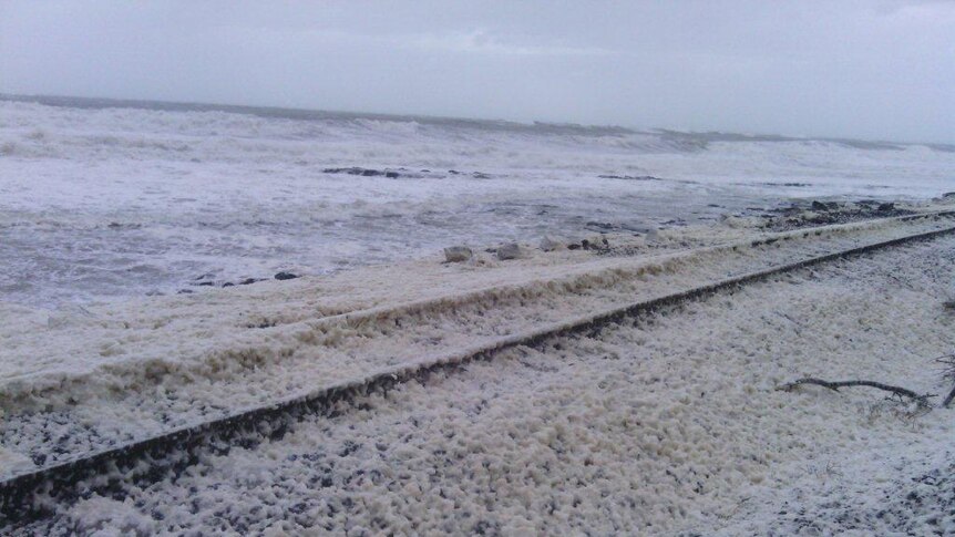 The railway at Sulphur Creek covered in foam whipped up by wild seas near Burnie in Tasmania's north-west.