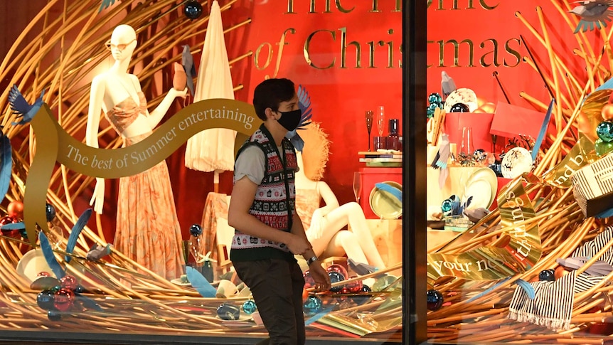 A shopper wearing a mask walks past a Christmas display outside a David Jones department store