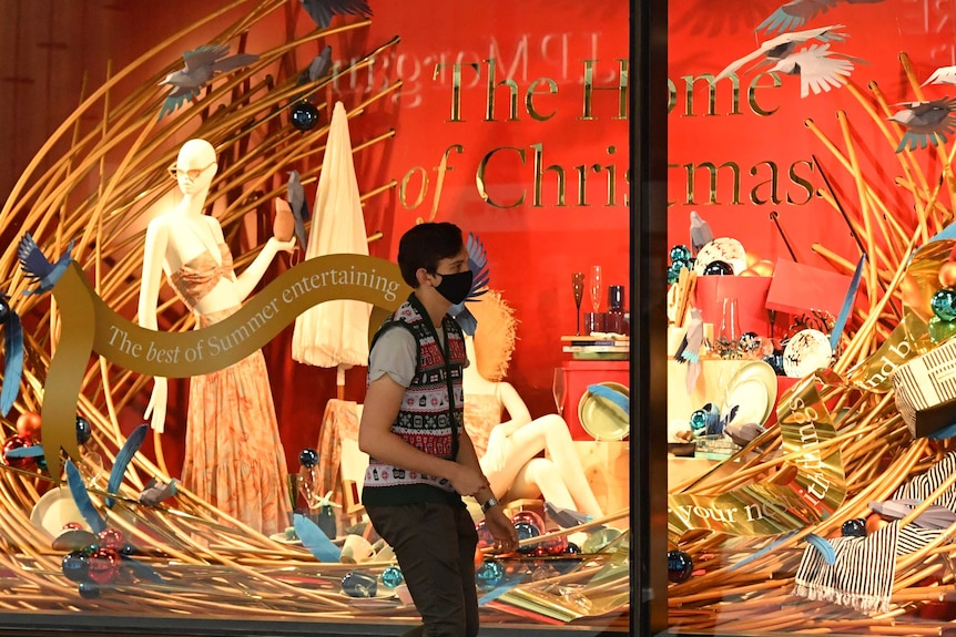 A shopper wearing a mask walks past a Christmas display outside a David Jones department store