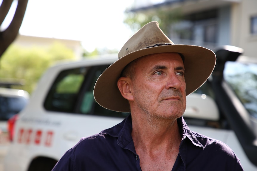 Greig Taylor of Charter North 4WD Safaris wears a hat in front of a white four-wheel-drive.