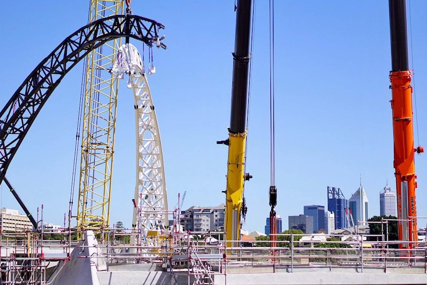 Cranes lift bridge arches onto support columns.