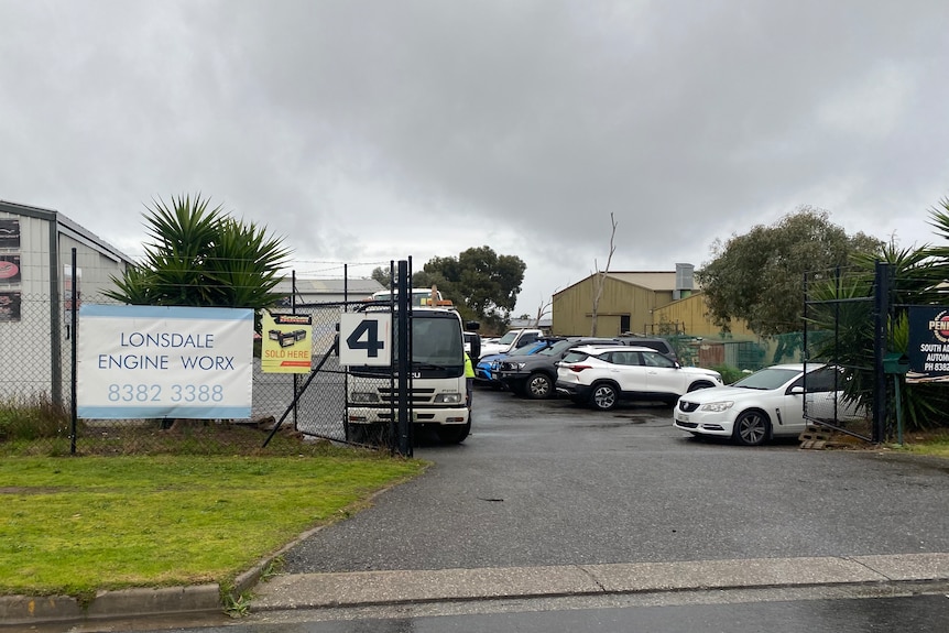 A car repairers with a chain fence and a truck inside a car park