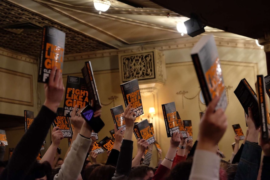 People in the audience at the launch of Clementine Ford's book Fight Like A Girl hold up their copies.