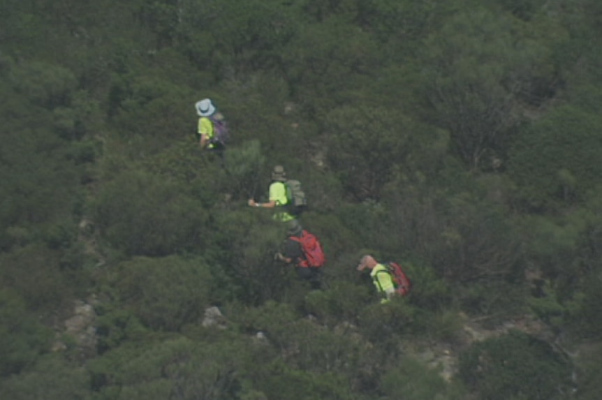 An aerial view of four bushwalkers walking through rugged terrain in the Blue Mountains.