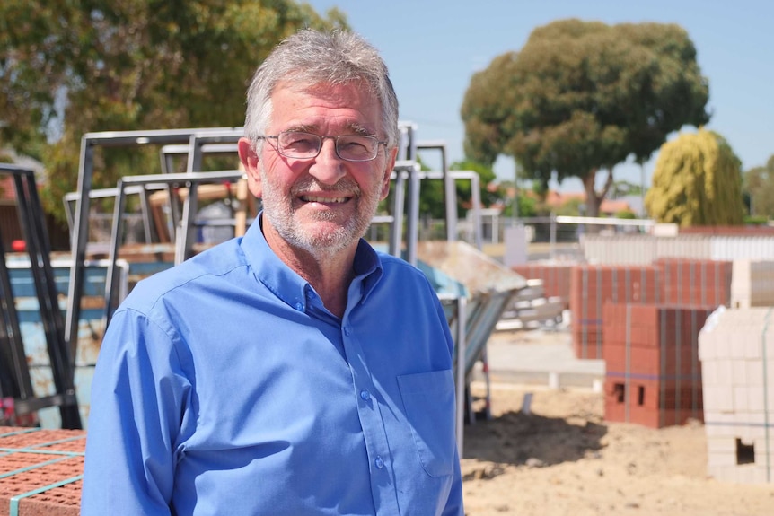 Stan Liaros in a blue shirt stands in a construction site.