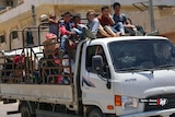Children sit atop a small truck, crammed with belongings