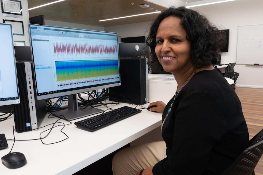 Dr Been Ahmed sitting in front of a computer with sound waves