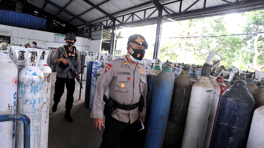 Police officers walk as they guard the oxygen distribution at a refill factory 