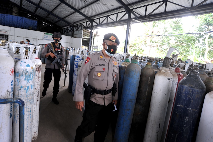 Police officers walk as they guard the oxygen distribution at a refill factory 