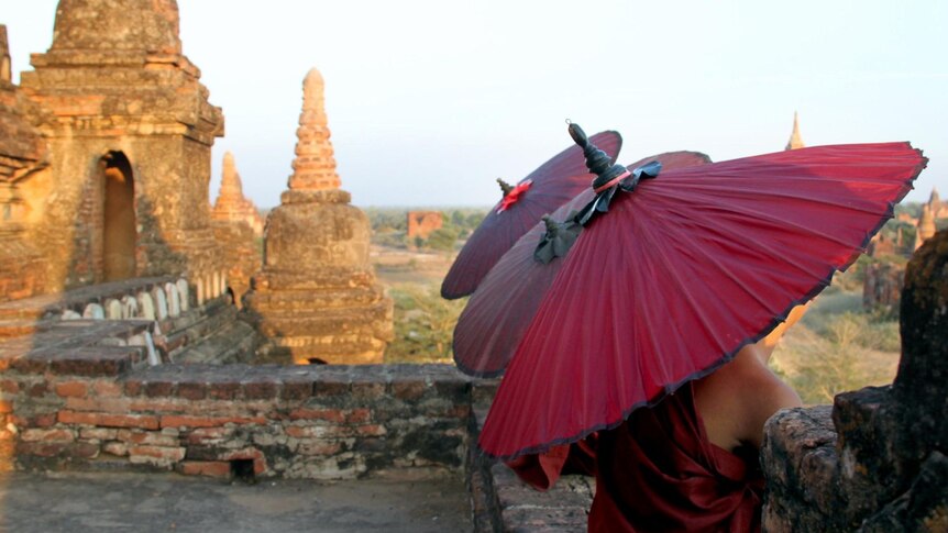 Young monks shelter under umbrellas at the Bagan temples site in Burma.