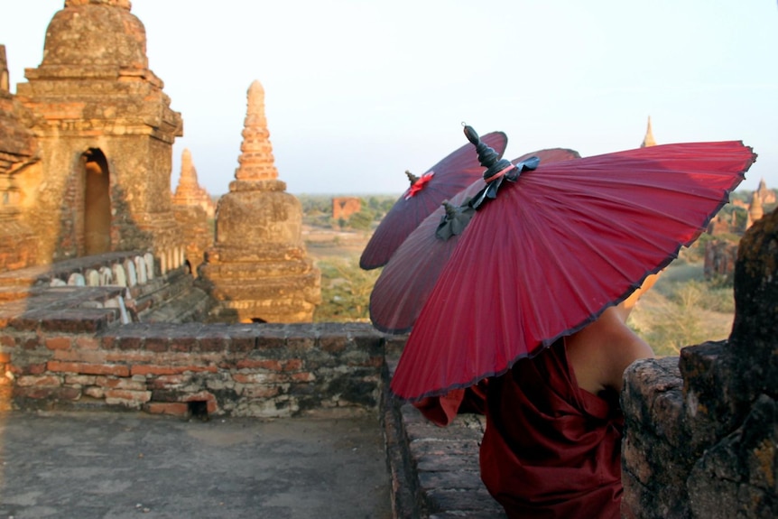 Young monks shelter under umbrellas at the Bagan temples site in Burma.