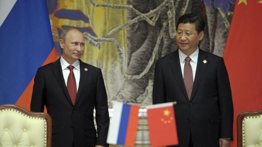 Russian President Putin and Chinese President Xi Xinping stand in front of Chinese and Russian flags